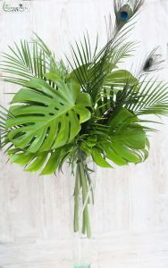 Botanical enterpiece in vase with palm leafs, monstera leafs and peacock feathers