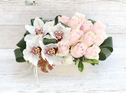 Modern composition with orchids and pink roses in a wooden box