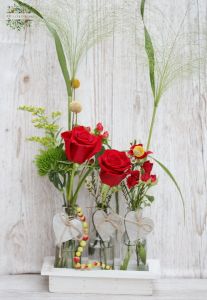 Vasendekorationen mit 3 rote Rosen in einer Holzschale