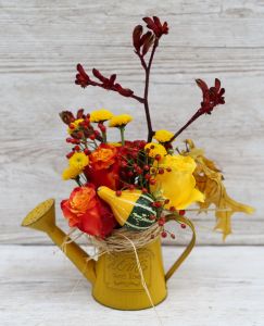 Herbstliche Gießkanne mit Kürbis und Rosen