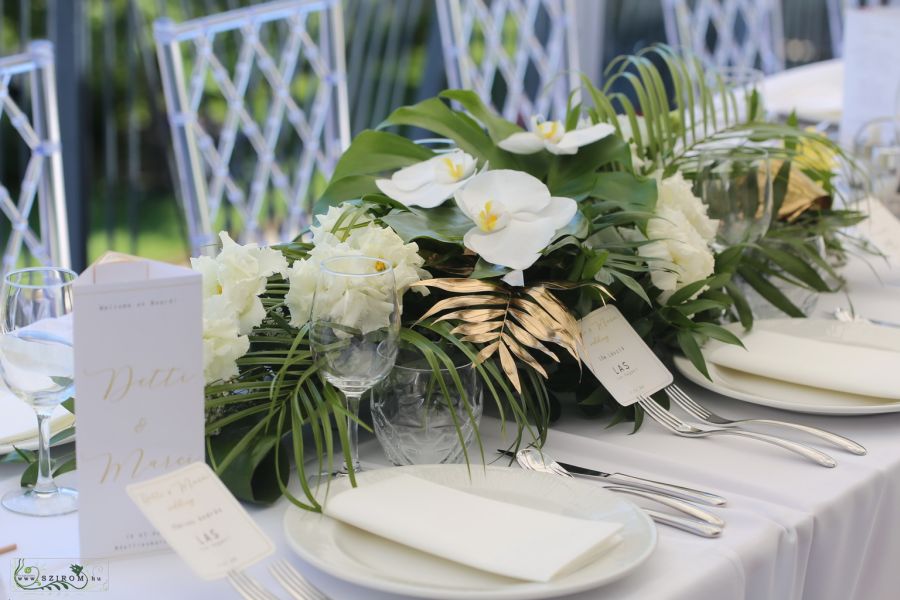 Hosszúkás esküvői asztaldísz, Bazaar Eclectica Étterem Budapest (phalaenopsis orhidea, lizianthus, monstera, pálmalevél, fehér, zöld, arany)