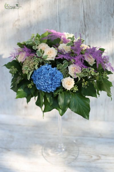 Magas esküvői asztaldísz kehely vázában (hortenzia, asparagus, bokros rózsa, barack, lila, kék)