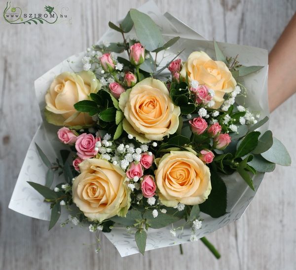 Peach roses with spray roses and gypsophila in a round bouquet
