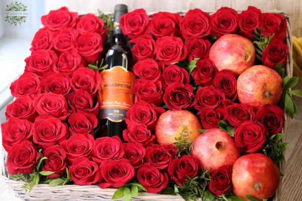 Rotwein in einem Bett aus 50 Rosen, mit Granatapfel