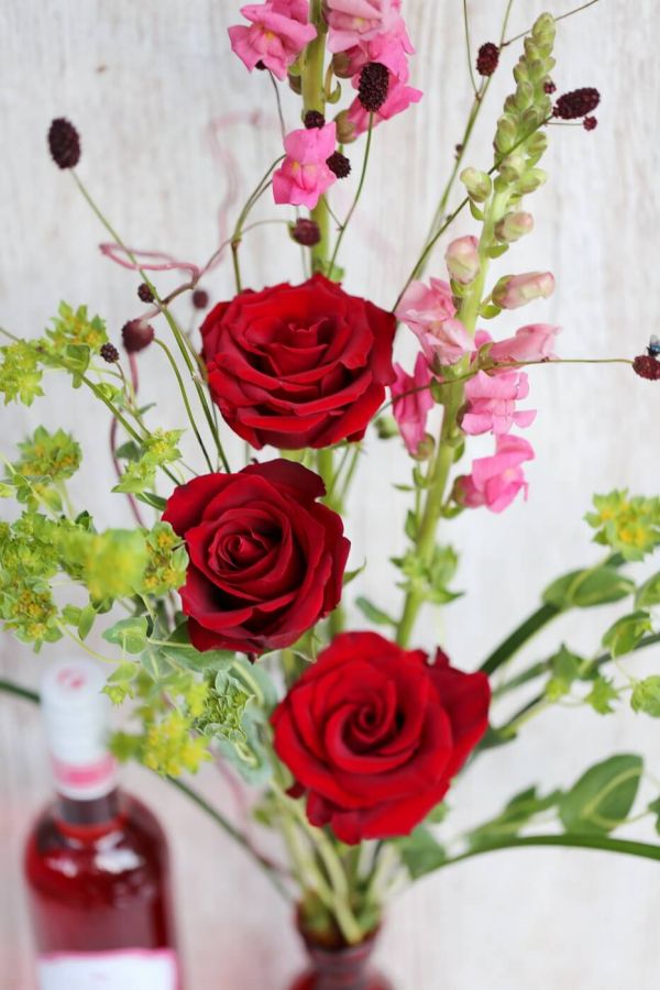 Red rose bouquet in vase, with rozé wine 