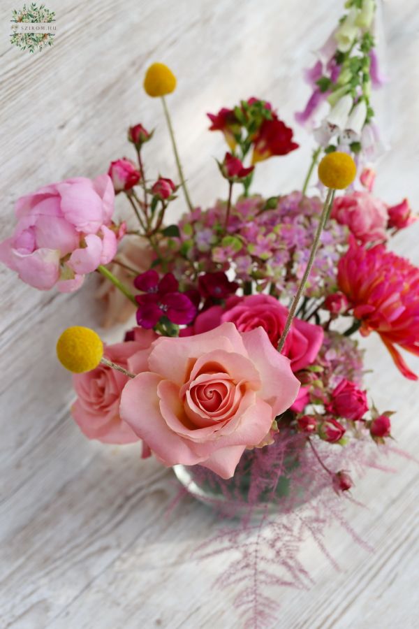 Luftiger Tafelaufsatz mit Saisonblumen in Glaskugel (rosa, rot, pfirsich)