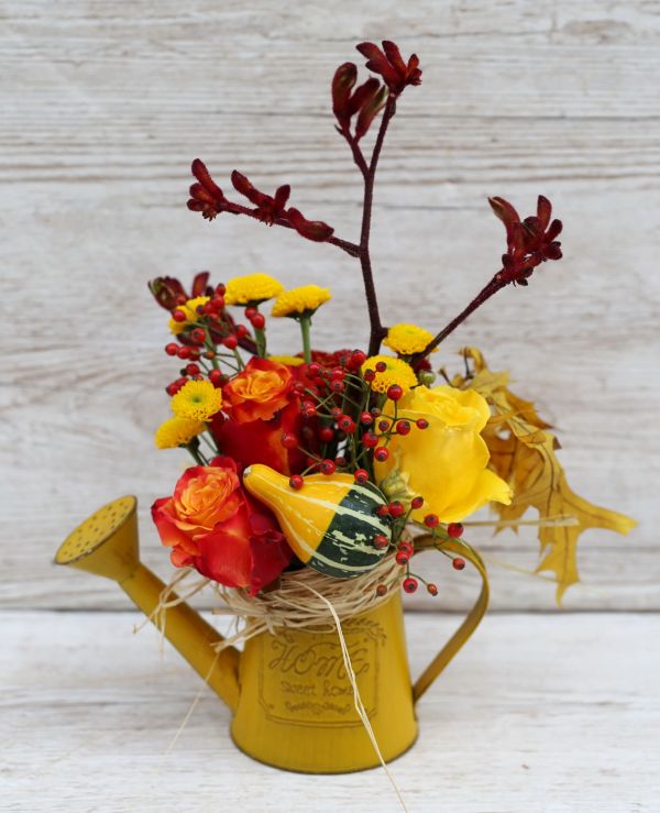 Herbstliche Gießkanne mit Kürbis und Rosen