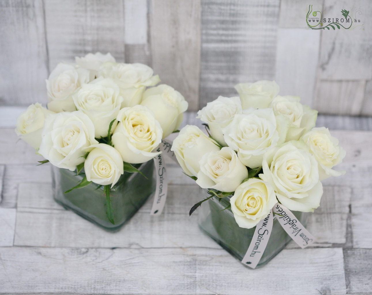 Asztaldísz üvegkockában fehér rózsákkal, esküvő